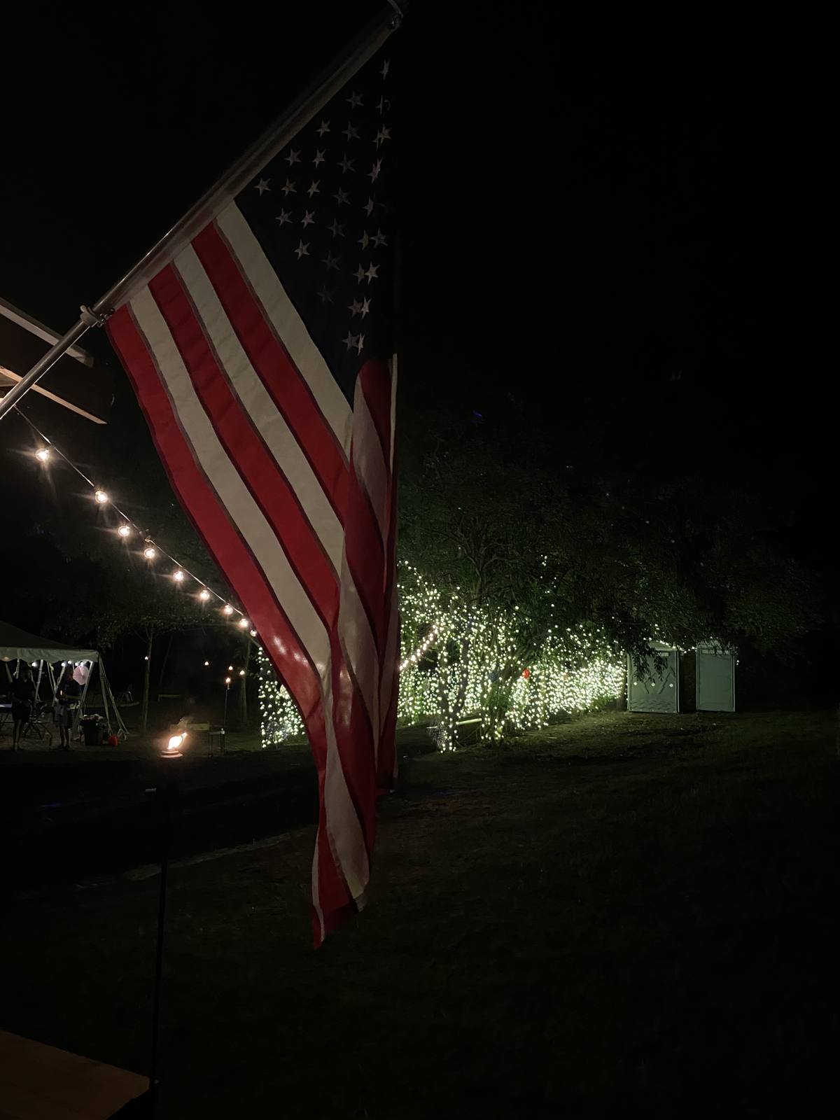An American flag lit up against the night sky