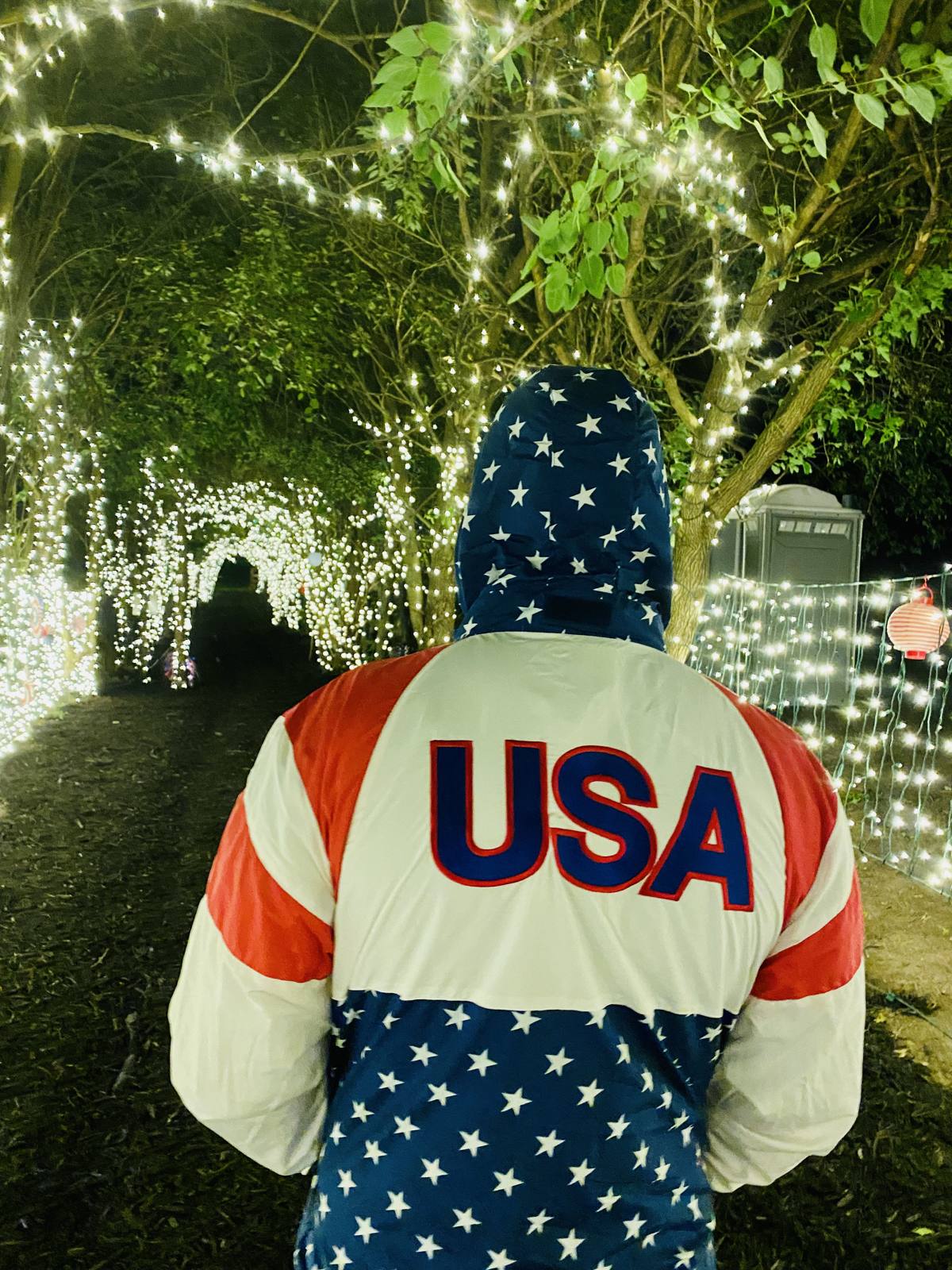 A guest in a USA jacket on the lit canopy walk at night