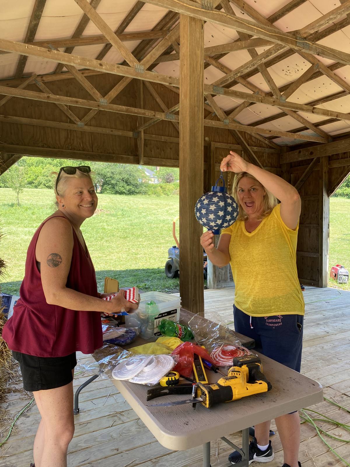 Two people decorating with patriotic lanterns under the barn